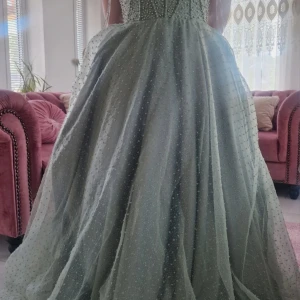 Mintgrön balklänning med pärlor och snörning - Säljer en magisk mintgröna balklänning med pärlbroderier över hela livet och tyllkjol. Klänningen har snörning i ryggen och en stor rosett baktill. Ärmlös modell med axelband i tyll och vacker volym i kjolen.jag köpte på 4000kr. Storlek mellan 38-42