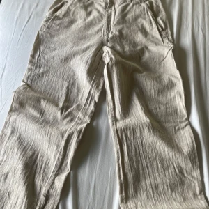 Beiga linne byxor från Kappahl - Säljer ett par beiga linne byxor från Kappahl i storlek 158. Byxorna har raka ben, sidfickor och är tillverkade i ett mjukt material som känns skönt mot huden. Perfekta för en avslappnad och stilren look. Ny pris runt 350-400