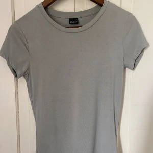 Ljusgrön t-shirt från Gina Tricot - En basic ljusgrön t-shirt från Gina Tricot med rund halsringning och korta ärmar. Perfekt att matcha med jeans eller kjol för en enkel och stilren look! jag vet att den ser lite grå ut men den är ljus grön!