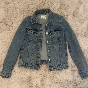 Blå jeansjacka från ZARA - Jeansjacka från Zara. Säljer då den ej kommer till användning. Jackan har inga tecken på användning. 