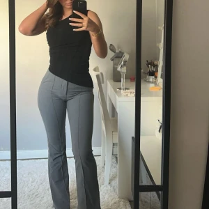 Grå kostymbyxor från Gina Tricot - Snygga grå kostymbyxor från Gina Tricot med klassisk passform och raka ben. Byxorna har pressveck framtill och sidfickor, perfekta för en stilren look. Materialet känns mjukt och har en lätt stretch. Bra skick!🩶