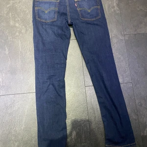 Levi's 512 Slim Jeans blå denim - Säljer ett par klassiska blå Levi's 512 Slim Jeans i denim med raka ben och snygga kontrastsömmar. Byxorna har fem fickor, gylf med dragkedja och knapp samt Levis ikoniska läderpatch bak. Perfekta för dig som gillar tidlös stil. Det passar pojkar 14-16 år. Bara provade.
