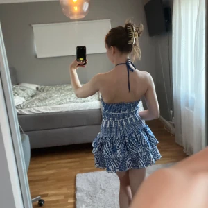 Kort klänning  - Supersöt blåvit klänning med volangkjol. Axelbandslös modell med knyt runt nacken. Bara använda en gång😊 pris kan diskuteras 