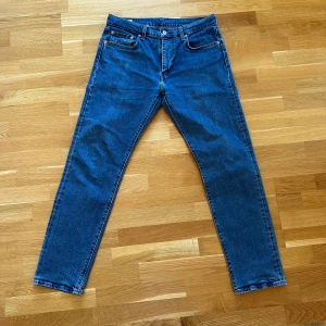 Levi's 502 blå jeansbyxor - Säljer ett par klassiska blå Levi's 502 jeans med raka ben och normal passform. Byxorna har fem fickor, dragkedja och knapp i midjan samt den ikoniska läderpatchen bak. Perfekta för dig som gillar tidlös denimstil.