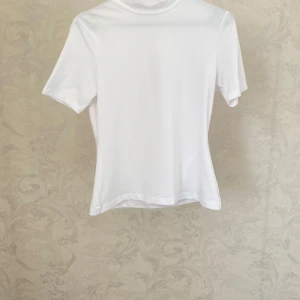 Vit och svart t-shirt med hög hals - Paket med Två stilrena t-shirts med hög hals, en i vitt och en i svart. Endast provat!