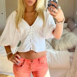 Vit blus med puffärmar från Linne Blend - Superfin vit blus med puffiga trekvartsärmar och v-ringning. Blusen har knappar framtill och är croppad, perfekt till sommaren. Tillverkad i en linneblandning som känns sval och skön. Aldrig använt