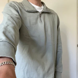 Ljusgrå långärmad tröja med halv dragkedja från Weekday - Säljer en stilren ljusgrå långärmad tröja från Weekday med halv dragkedja vid kragen. Tröjan har en klassisk passform och är tillverkad i mjuk bomull, perfekt för en avslappnad look.