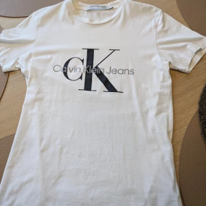 Vit t-shirt från Calvin Klein Jeans  - Vit T-shirt från Calvin Klein Jeans i storlek S med klassisk CK-logga framtill. Endast använd en gång och i mycket fint skick – ser i princip ny ut. Nypris ca 500 kr. Köparen betalar frakten. Pris: 220 kr – lite prutbart vid snabb affär.