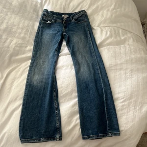 Blå bootcut jeans från Gina Tricot - Säljer ett par klassiska blå bootcut jeans från Gina Tricot i storlek 152. Jeansen har normal passform, två knappar framtill och fickor både fram och bak. Perfekta för dig som gillar en tidlös denimlook.