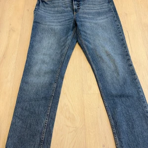 Blå raka jeans i klassisk modell - Säljer ett par blå jeans med rak passform och klassisk femficksdesign. Jeansen har en snygg tvättad look och är tillverkade i slitstarkt denimtyg. Perfekta för dig som gillar en tidlös stil och vill ha ett par jeans som funkar till det mesta.