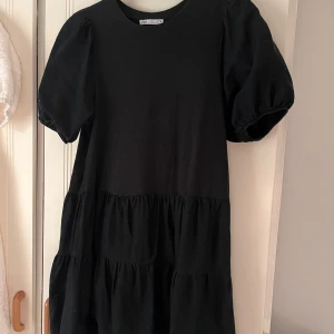 Svart klänning från Zara - Jättegullig svart kortklänning från Zara med puffärmar som passar mig som är XS men även större storlekar! Luftig och helt perfekt för sommaren, och säljer för att ha råd med min student! 