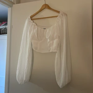 Vit blus med puffärmar från SHEIN - Supersöt vit blus från SHEIN med croppad passform och långa puffärmar. Toppen har en fyrkantig urringning och är gjord i ett lätt, tunt tyg som ger en romantisk vibe. Perfekt att styla med jeans eller kjol för en trendig look.