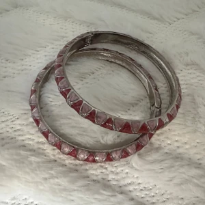 Silvriga armband med rosa detaljer - Två stycken chunky armband i silverfärgad metall med coola rosa och ljusrosa triangeldetaljer runt om. Armbanden har gångjärn för enkel påtagning och ger en unik, edgy vibe till din outfit.