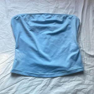 Ljusblå tubtopp från SHEIN - Säljer en enkel och snygg ljusblå tubtopp från SHEIN i storlek XS. Toppen är bandeau-modell och ärmlös, perfekt för varma dagar. Tillverkad i mjukt och stretchigt syntetmaterial som sitter skönt mot kroppen.