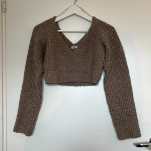 Brun croppad stickad tröja Gina Tricot XS - Supermysig croppad stickad tröja från Gina Tricot. Tröjan har v-ringning, lång ärm och ribbad struktur. Från Ginas ’Premium quality’ kollektion. Materialet kan upplevas stickigt mot huden.
