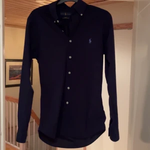 Mörkblå skjorta från Ralph Lauren - Säljer en mörkblå slim fit skjorta från Ralph Lauren || Skick 9/10 || Storlek S ||Skriv om ni har några funderingar!