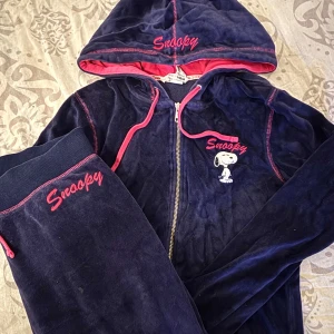 Mörkblå Snoopy hoodie med dragkedja och mjukis byxor från H&M - Mysig mörkblå/mörklilla  hoodie från H&M med Snoopy-brodyr och rosa detaljer. Jackan har dragkedja, huva med rosa foder och snörning samt broderad Snoopy-text på bröstet och huvan. Byxorna ingår också,dom är väldigt sköna och sitter väldigt bra på. Det står dok att dom e xs men jag skulle vilja säga att dom är s .🩷Perfekt för chill dagar eller när du vill ha något bekvämt och snyggt. 🩷💗💋