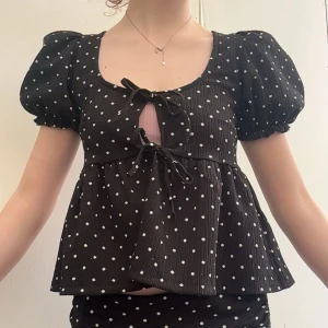 Svart prickig blus med puffärm och knyt - Supersöt blus från Gina tricot som är helt öppen fram med knytning! Användt väldigt få gånger, inget fel på den utan säljer den för att det inte är min stil