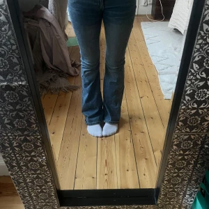 Blå bootcut jeans från Weekday - Säljer ett par snygga blå bootcut jeans från Weekday, modell Flame. Jeansen har låg midja och klassisk femficksdesign. Materialet är jeans i bomull med lite stretch för skön passform.