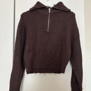 Brun stickad half zip-tröja Gina Tricot - Mysig brun stickad tröja från Gina Tricot i croppad modell. Tröjan har en hög krage med half zip-dragkedja och långa ärmar. Perfekt för lager-på-lager och chill höst- och vinterstil.