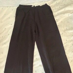 Svarta mjukisbyxor med resårmidja - Svarta mjukisbyxor med breda, raka ben och elastisk midja. Perfekta för chill dagar eller när du vill ha det extra bekvämt. mjukt material som känns skönt mot huden.