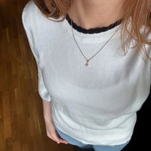 Vit topp med volangärm - Supersöt vit topp från Topshop med svarta detaljer vid halsen och volang på trekvartsärmarna. Perfekt till jeans för en chill men ändå stylish look. Mjuk och skön i bomullsmix, passar både till vår och höst.