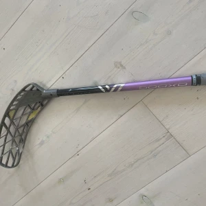 OXDOG Ultimate Light - Snygg och lätt innebandyklubba från OXDOG, perfekt för dig som vill ta ditt spel till nästa nivå. Klubban har en cool lila och svart design och är utrustad med ett greppvänligt handtag. Viss slitage syns på skaftet, men den är fortfarande i bra skick för match eller träning.