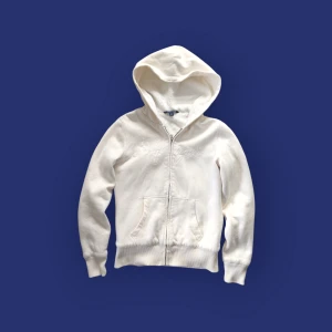 Vit fur hoodie från Tommy Hilfiger - Säljer en creme färgad/vit hoodie från Tommy Hilfiger med dragkedja och huva. Den har en mjuk, fluffig insida och ribbade muddar vid ärmslut och nederkant. Storlek XS.