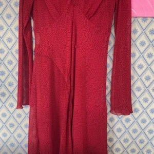 Röd prickig klänning - Snygg röd klänning med svarta prickar och lång ärm. Den har en v-ringad design och en subtil slits framtill. Lite mindre i storlek:) Endast använd 2ggr