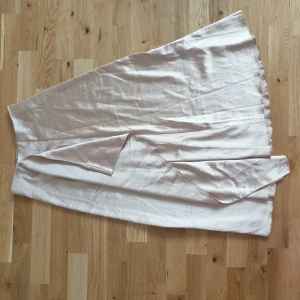 Beige satin omlottkjol  - Snygg beige omlottkjol från Shein i ett mjukt och glansigt material. Kjolen har en elegant omlottdesign som ger en fin siluett. Perfekt för att skapa en stilren look.