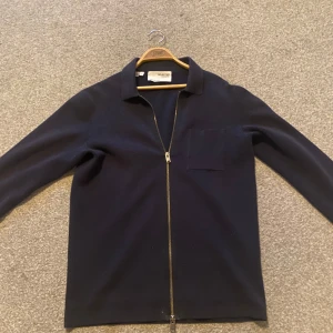 Mörkblå tröja med dragkedja från Selected Homme - Säljer en stilren mörkblå tröja från Selected Homme. Tröjan har en praktisk dragkedja framtill och en klassisk krage. Perfekt för en avslappnad men ändå snygg look.