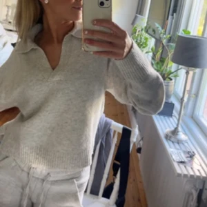 Grå tröja från Monki - Säljer en stilren grå stickad tröja från Monki. Tröjan har en v-ringad design med långa ärmar och ribbade detaljer vid ärmslut och nederkant. 