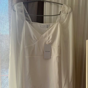 Vit klänning från Vila - Elegant vit klänning från Vila med långa ärmar och en v-ringad design. Klänningen har en stilren look och är perfekt för speciella tillfällen som student dagen. Tillverkad i ett mjukt och bekvämt material som ger en fin passform. Köparen står för frakten! Pris kan diskuteras💖