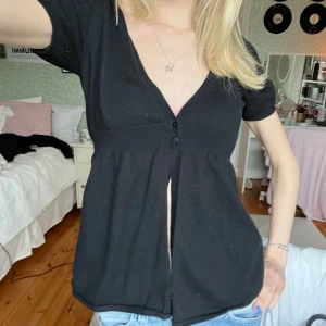 Svart kortärmad topp - Säljer en svart kortärmad topp med knappar framtill. 