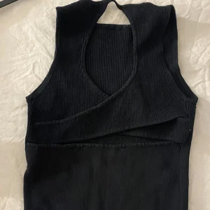 Svart ribbad linnetopp från Zara - Snygg svart ribbad linnetopp från Zara. Toppen har en omlott-design och är ärmlös, den går att ha åt båda hållen och är i nyskick 