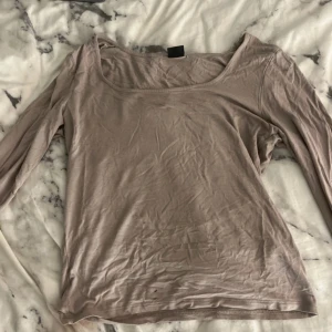 Beige långärmad topp från Bik Bok - Säljer en beige långärmad topp från Bik Bok. Toppen är i ett mjukt material och har en enkel design med rund halsringning. Perfekt för en avslappnad look. Slit vid handleden