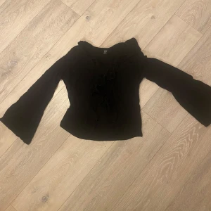 Svart topp från Shein - Säljer en svart topp från Shein med långa ärmar och snygg snörning framtill. Perfekt för en stilren look.