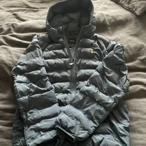 Lyle&scott jacka - Säljer en pufferjacka från Lyle & Scott. Jackan har en dragkedja framtill och en huva för extra skydd mot väder. Perfekt för kyligare dagar. Passar xs, blå aktig, pris kan diskuteras