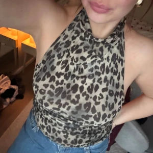 Leopardmönstrad halterneck topp - Använd en  gång! Säljer en snygg leopardmönstrad halterneck topp med öppen rygg. Perfekt för att ge en djärv touch till din outfit. Toppen har en tight passform och är tillverkad i ett mjukt och stretchigt material.