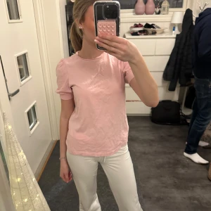 Rosa t-shirt från Vero Moda - Säljer en söt rosa t-shirt från Vero Moda. Den har korta ärmar med en lätt puffig design och en rund halsringning. Perfekt för en avslappnad stil. Dock är de lite små fläckar back på tröjan men dem syns inte mycket alls. Snygg sommar tröja🥰💘🎀🤩