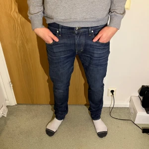 Mörkblå jeans från tiger of sweden - Säljer ett par mörkblå jeans från tiger of sweden i riktigt snygg tvätt. Modellen på jeansen är pistolero o sitter snyggt slim. Storleken är 31 i midja och 32 i längd. Kom privat vid fler frågor!