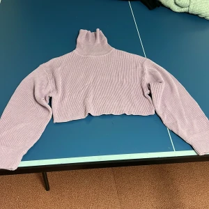 Lila ribbad croppad polotröja från Divided - Säljer en snygg lila ribbad polotröja från Divided. Tröjan är croppad med långa ärmar och en hög polokrage