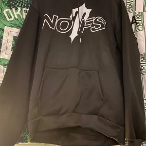 Svart hoodie med tryck - Säljer en svart hoodie med ett coolt tryck på framsidan. Den har en klassisk känguruficka och en bekväm passform. Perfekt för en avslappnad stil.