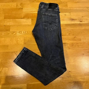 Mörkblå jeans från Replay - Snygga svarta jeans från Replay med slitningar. Jeansen är i nyskick. Storlek W33 L32.