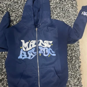 Navy blue made havoc hoodie - Säljer en blå hoodie med ett coolt tryck på framsidan. Hoodien har en dragkedja och en luva, perfekt för en avslappnad stil. Det finns även ett tryck på ärmen. Passar bra för kyligare dagar.