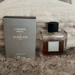 L'Homme Idéal Eau de Parfum från Guerlain - Upptäck L'Homme Idéal Eau de Parfum från Guerlain, en elegant doft i en stilren, fyrkantig flaska med svart kork. Förpackningen är grå och stilren, vilket ger en lyxig känsla. Perfekt för den moderna mannen som vill utstråla självsäkerhet och elegans.  Framträdande noter är körsbär, äkta vanilj & kyrkligrökelse! Detta är en 100ml flaska men består av minst 60ml kvar... 