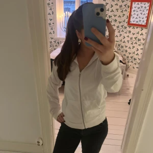 Vit hoodie - Säljer en stilren vit hoodie med dragkedja och huva. Perfekt för en avslappnad look. Den har långa ärmar och en bekväm passform.