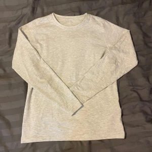 Grå långärmad tröja från fribo - Säljer en stilren grå långärmad tröja. Perfekt för lager-på-lager eller som den är. Tröjan har en enkel design med rund hals och är tillverkad i ett mjukt material.