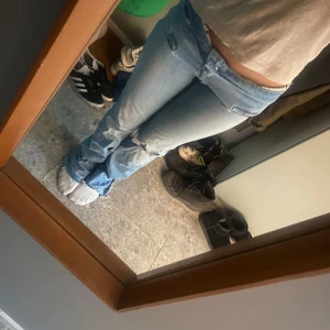 Blå bootcut jeans med hål - Säljer ett par ljusblå bootcut jeans med slitningar på knäna. För långa för mig som är ungefär 163. Har ett litet hål på baksidan så kom privat för flera bilder storlek S❣️