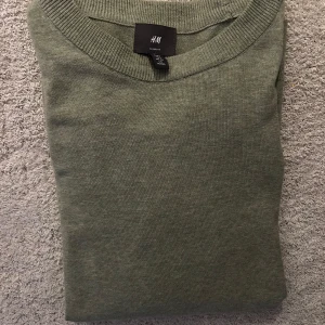 Grön tröja från H&M - Säljer en stilren grön tröja från H&M i storlek S. Tröjan har en klassisk rund halsringning och är perfekt för både vardag och avslappnade tillfällen. Den är tillverkad i ett mjukt material som ger en bekväm passform.